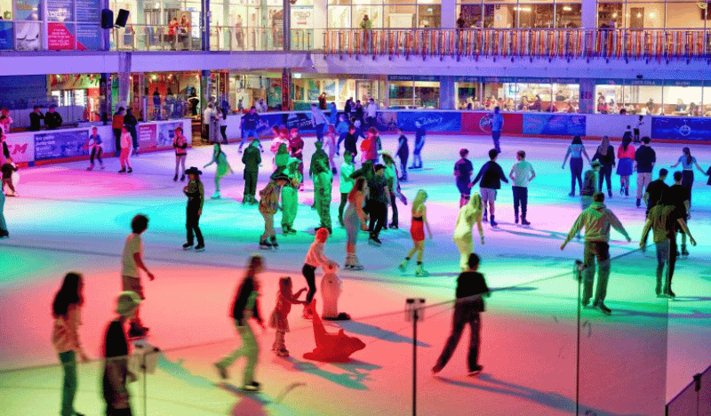 Photo of a crowded ice rink with disco lights